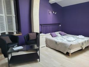 Saint-Victor-de-MalcapにあるLes parfums du midiの紫の壁のベッドルーム1室、ベッド1台、椅子2脚が備わります。