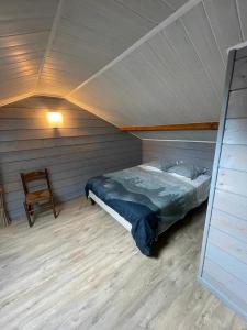 1 dormitorio con 1 cama y 1 silla en el ático en le Pigeonnier gersois, en Condom
