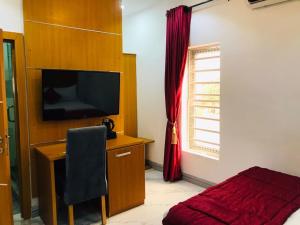 um quarto com uma cama, uma secretária e uma televisão em Dominance Events and Suites em Ibadan