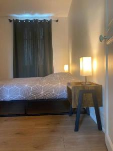 een slaapkamer met een bed en een tafel met een lamp bij Appartement Centre Ville in Nevers