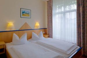 Schlafzimmer mit einem Bett mit weißer Bettwäsche und einem Fenster in der Unterkunft Sporthotel Malchow Hotel Garni HP ist möglich in Malchow
