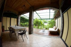 a patio with a table and chairs and a couch at Soul Sync Sanctuary formally Hacienda la Moringa in Playa Hermosa