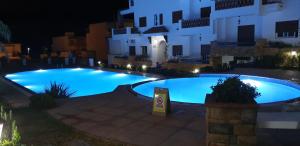 a large swimming pool in front of a building at night at Appart. 4pc à 150m², vue mer et pieds dans léau in Oued Laou