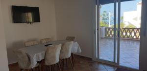 a dining room with a table and chairs and a balcony at Appart. 4pc à 150m², vue mer et pieds dans léau in Oued Laou