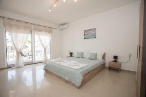 a white bedroom with a bed and a large window at Three Palms in Gevgelija