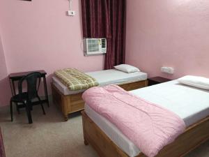 a room with two beds and a table and a chair at Ananya Homestay in Patna
