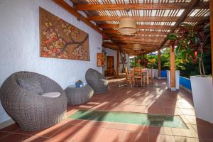 a patio with wicker chairs and a table and a painting at Blu Galapagos Sustainable Waterfront Lodge in Puerto Ayora