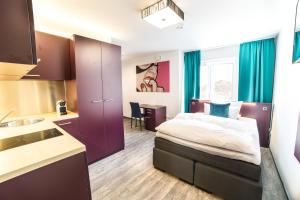 a hotel room with a bed and a kitchen at Luxstay Friedberg - Self-Check-In in Friedberg