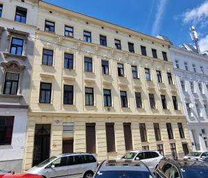un grand bâtiment avec des voitures garées devant dans l'établissement ViennaSunshine, à Vienne