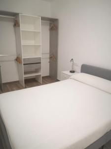 Un dormitorio con una gran cama blanca y estanterías en Apartament LA SAL, en Pineda de Mar