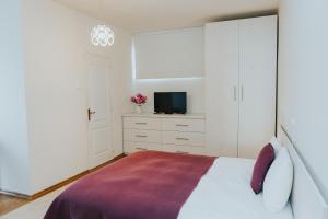 Camelia's cozy place في بايا ماري: غرفة نوم مع سرير وتلفزيون في خزانة