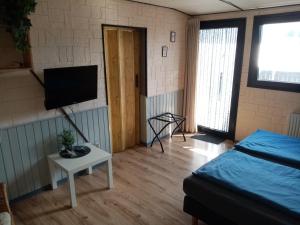 a room with a bed and a tv and a table at Pension Hubertus in Oberraden
