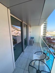 - un balcon avec une table et des chaises en verre dans un bâtiment dans l'établissement Ardwyn Studio Apartments Gibraltar, à Gibraltar