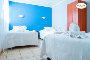 a room with two beds with white sheets and a blue wall at Hotel Portal del Norte in Copiapó