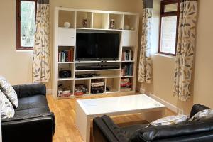 un salon avec un canapé et une télévision dans l'établissement Woodside Cottages - Ash cottage (self-catering), à Uckfield
