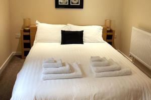 un lit blanc avec des serviettes dessus dans l'établissement Woodside Cottages - Ash cottage (self-catering), à Uckfield