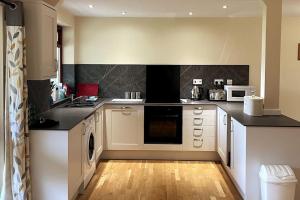 une cuisine avec des armoires blanches et des comptoirs noirs dans l'établissement Woodside Cottages - Ash cottage (self-catering), à Uckfield