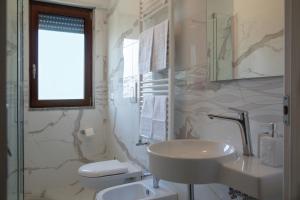 La salle de bains blanche est pourvue d'un lavabo et de toilettes. dans l'établissement Villa Vilù, à Bellosguardo