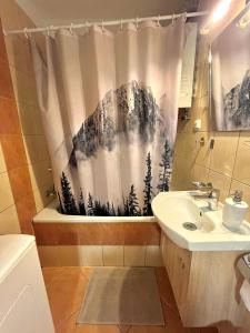 a bathroom with a shower curtain with trees on it at Apartament Kościuszki in Świnoujście +13 photos
