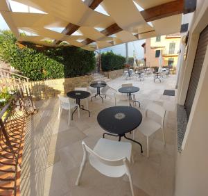 d'une terrasse avec des tables noires et des chaises blanches. dans l'établissement Villa Vilù, à Bellosguardo