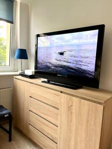 a flat screen tv sitting on top of a wooden cabinet at Apartament Kościuszki in Świnoujście