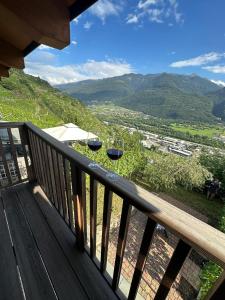 two wine glasses sitting on a deck with mountains in the background at Casa dell'Olivo in Castione Andevenno