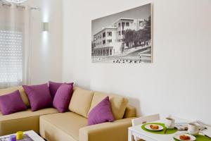 sala de estar con sofá y almohadas moradas en Eshkol Housing Haifa -Executive Apartments, en Haifa