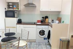 a kitchen with a washing machine and a table and chairs at Modern Spacious Detached Cottage in Cambridge in Cherry Hinton
