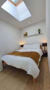 a bedroom with a bed with white sheets and a skylight at Modern Spacious Detached Cottage in Cambridge in Cherry Hinton
