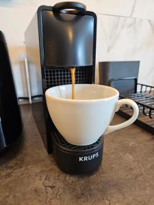 eine Kaffeemaschine schüttet Kaffee in eine Tasse in der Unterkunft Anomis Infinity Pool & SPA Resort Sea-View in Mamaia Nord – Năvodari