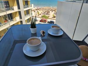due tazze di caffè su un tavolo di vetro sul balcone di Anomis Infinity Pool & SPA Resort Sea-View a Mamaia Nord - Năvodari