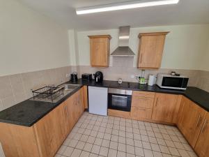 een keuken met houten kasten en zwarte aanrechtbladen bij Donard View Apartment in Newcastle +6 foto's