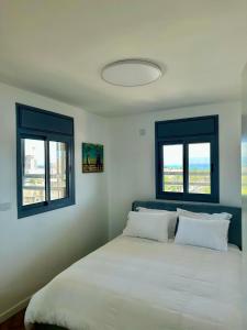 a bedroom with a large bed with two windows at Suite In White in ‘Akko