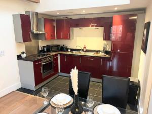 una cucina con armadi rossi e un tavolo con sedie di City Center 2 bedrooms Apartment a Manchester