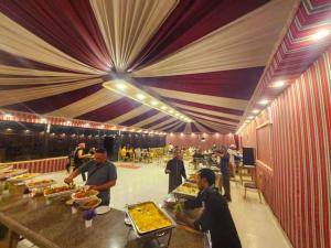 a buffet line with people preparing food in a restaurant at Wadi Rum Aviva camp in Wadi Rum