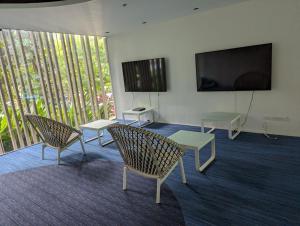 Habitación con sillas, mesas y TV de pantalla plana. en Dominiks Stylish Resort Gem Ocean View Pool Queen Bed at Tambuli 8 Floor Fast Wifi en Maribago