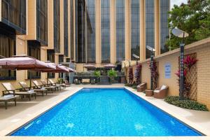 a swimming pool with chairs and umbrellas next to a building at Element by Westin Hotel Dar es Salaam in Dar es Salaam