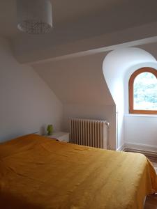 a bedroom with a bed with a yellow bedspread and a window at Appartement cosy pour une pause sereine et chaleureuse in Le Mont-Dore