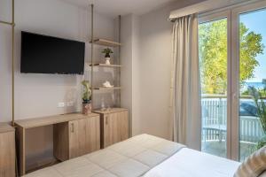 Schlafzimmer mit einem Bett, einem TV und einem Balkon in der Unterkunft Salus Smart & Chic Hotel in Lido di Jesolo