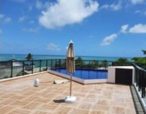 嘎林海斯港的住宿－Maracaipe condomínio novo, apartamento 103，一个带遮阳伞的庭院和背景海洋