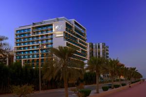 un grand bâtiment avec des palmiers devant lui dans l'établissement Aloft Palm Jumeirah, à Dubaï