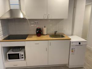 eine Küche mit weißen Schränken, einer Spüle und einer Mikrowelle in der Unterkunft Cal Mestre- Olot in Olot