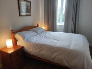 a bedroom with a bed with a night stand and a window at Bluebell House in Newry