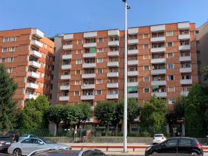 un edificio de apartamentos con coches aparcados en un aparcamiento en Appartamento incantevole a San Donato Milanese, en San Donato Milanese