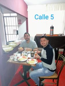 dos hombres sentados en una mesa comiendo comida en CALLE 5 - Lima AIRPORT, en Lima