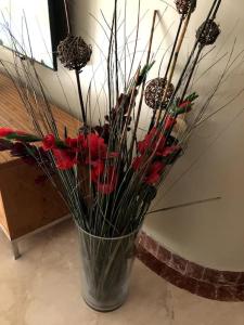 un vase rempli de fleurs rouges et de bâtons dans l'établissement Nitza Seaview Apartments, à Netanya