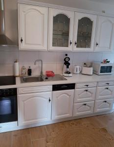 a kitchen with white cabinets and a sink at Haus Waldblick in Liebenwalde +8 photos