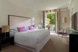 a bedroom with a large white bed with pink pillows at Sheraton Grand Salzburg in Salzburg