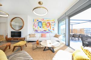 a living room with a white couch and a painting at The Radiant By HolyGuest in Tel Aviv