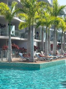 a group of people laying on chairs under palm trees in a pool at Casa Las Olas in Palm-mar